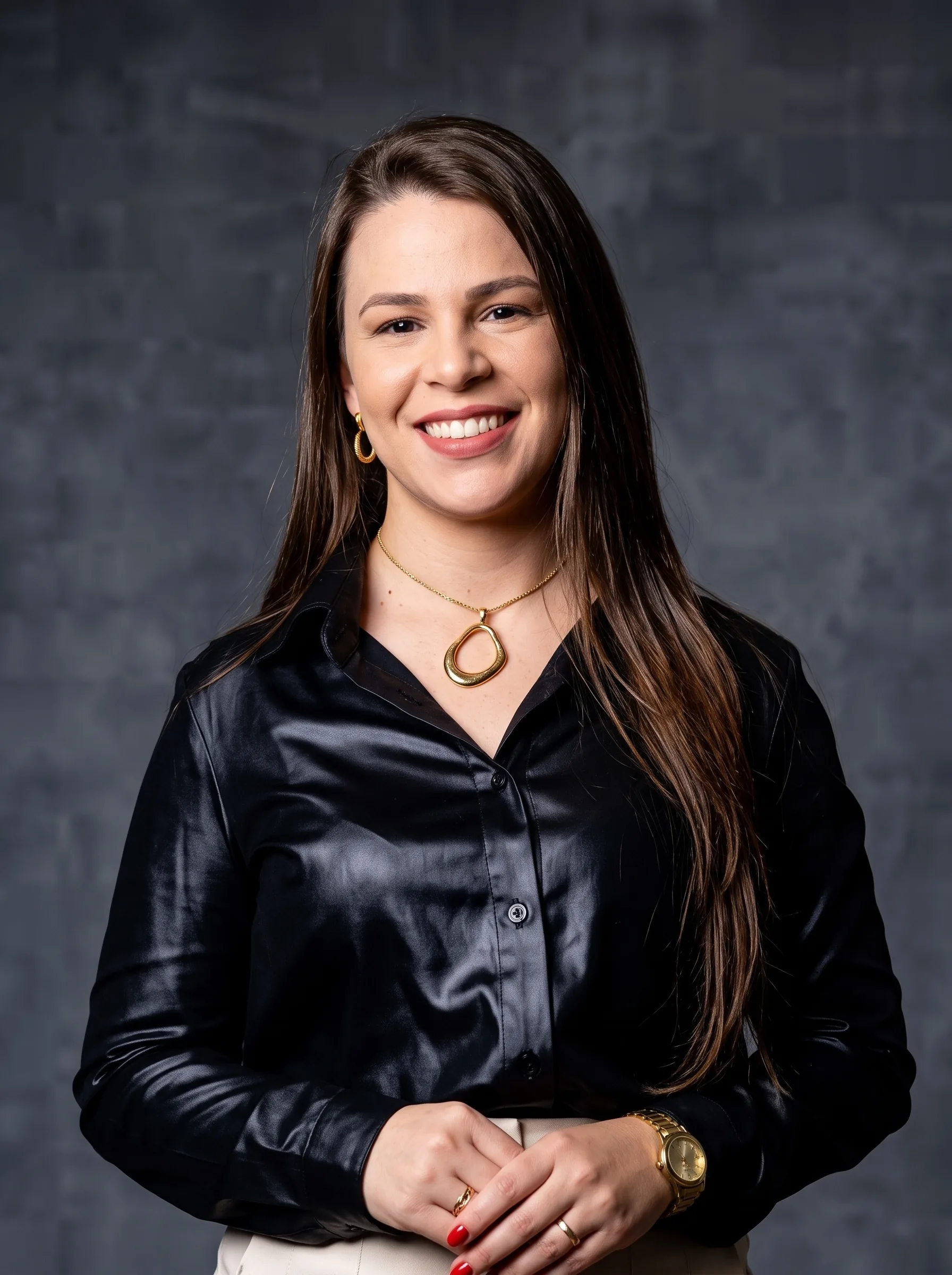 Vanessa Landvoigt, advogada, sorrindo, de camisa preta e colar dourado, sobre fundo cinza.